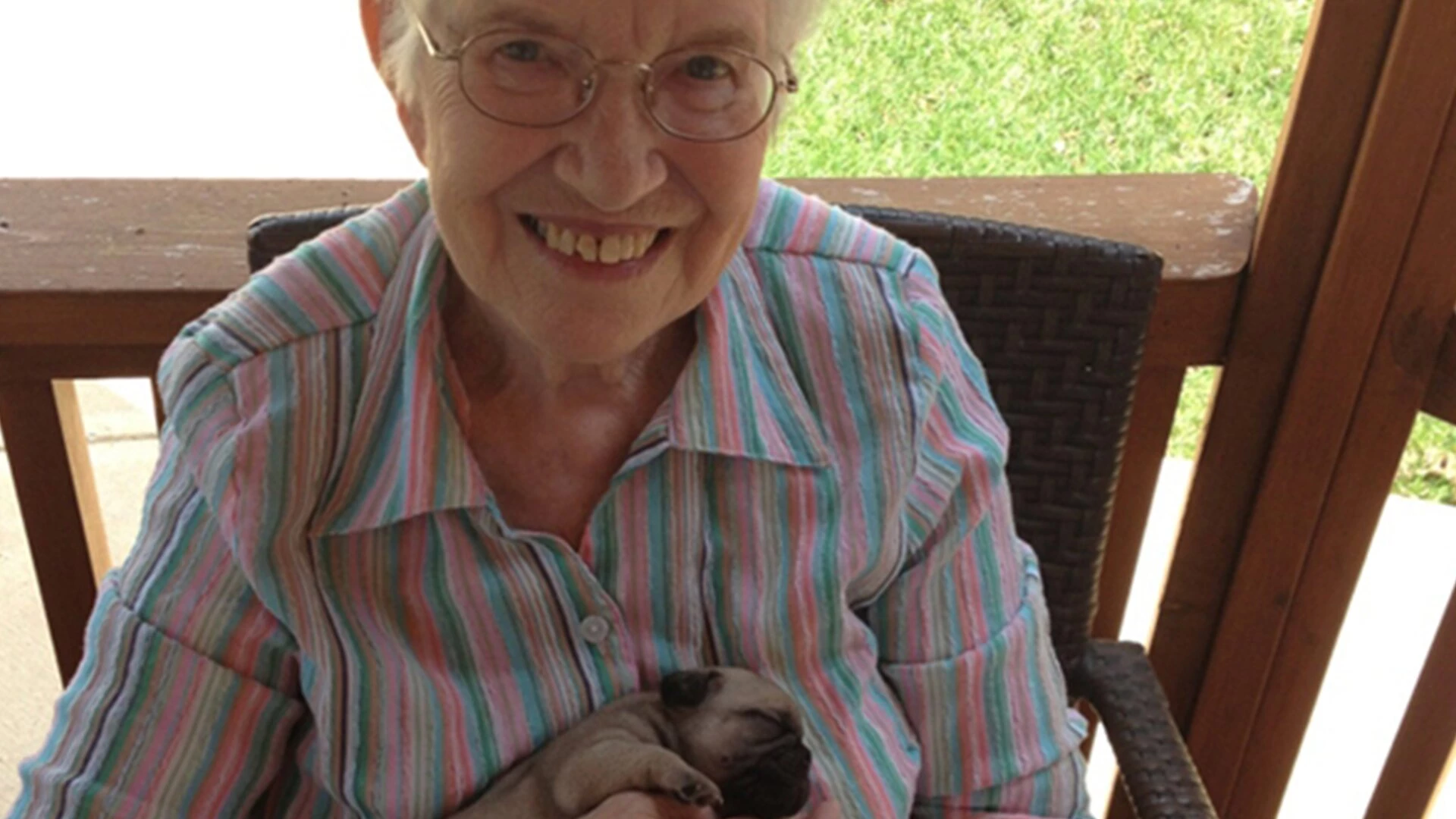 An elderly smiling while holding a puppy