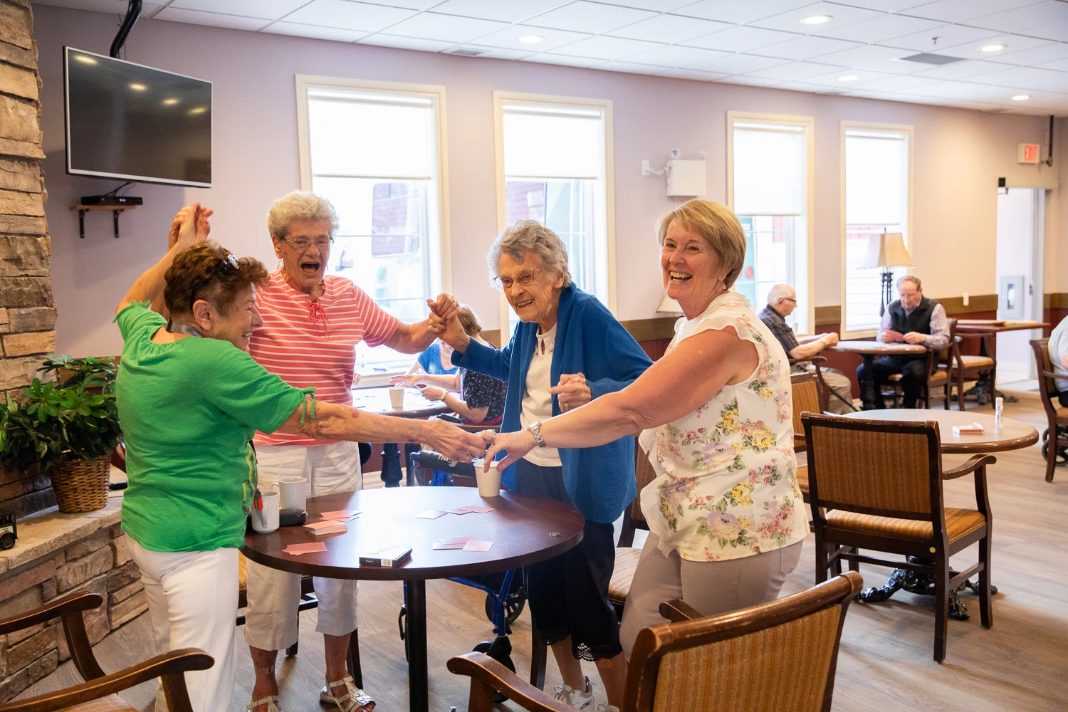 Seniors holding hands and cheering around a table