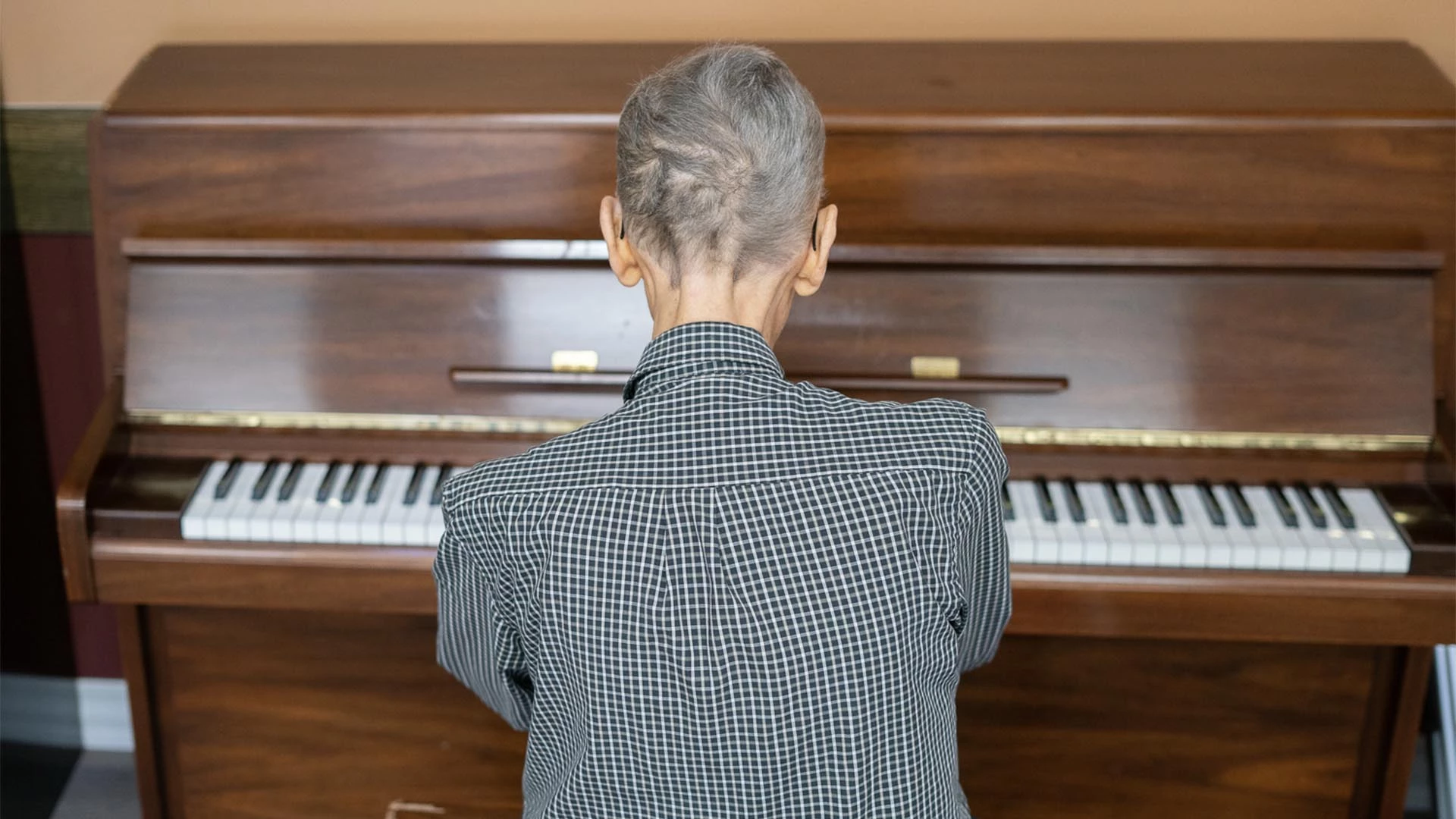 Man in a black and white collared shirt playing piano